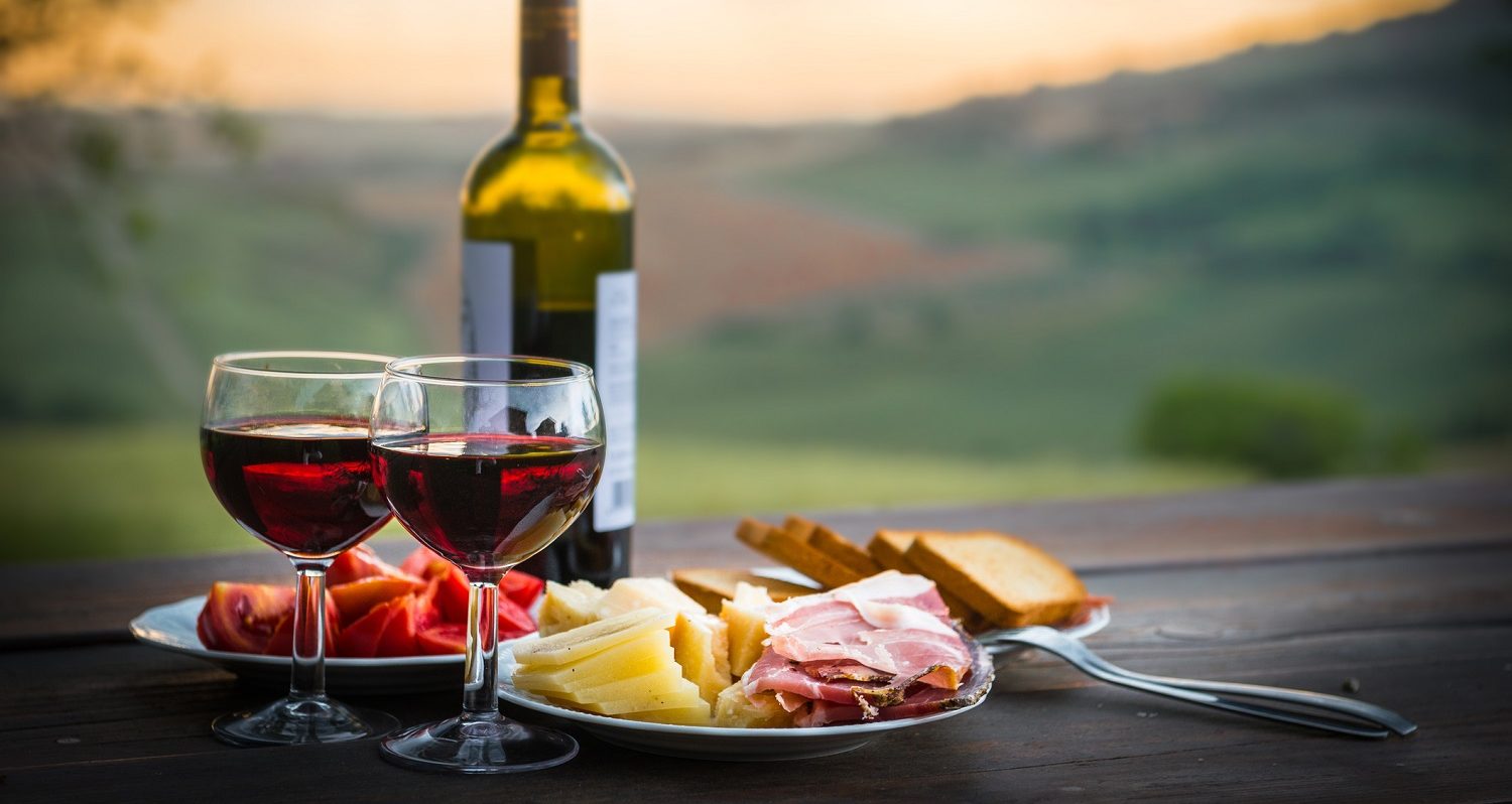 wine glasses and bottle with meat and cheese tray overlooking vineyard