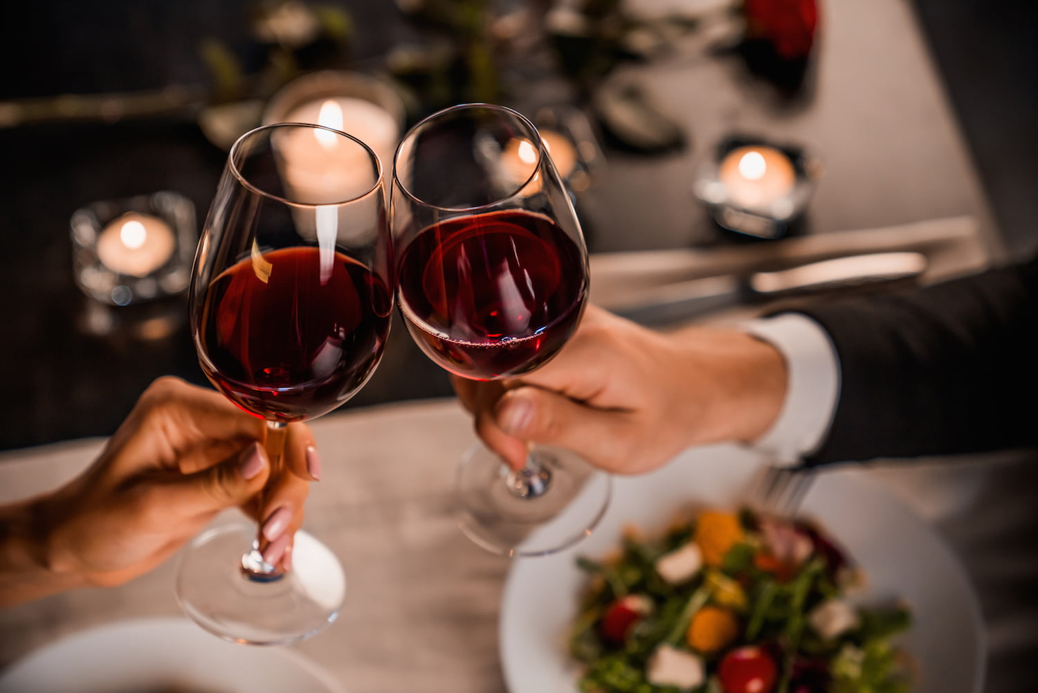 Close up of young couple toasting with glasses of red wine at restaurant