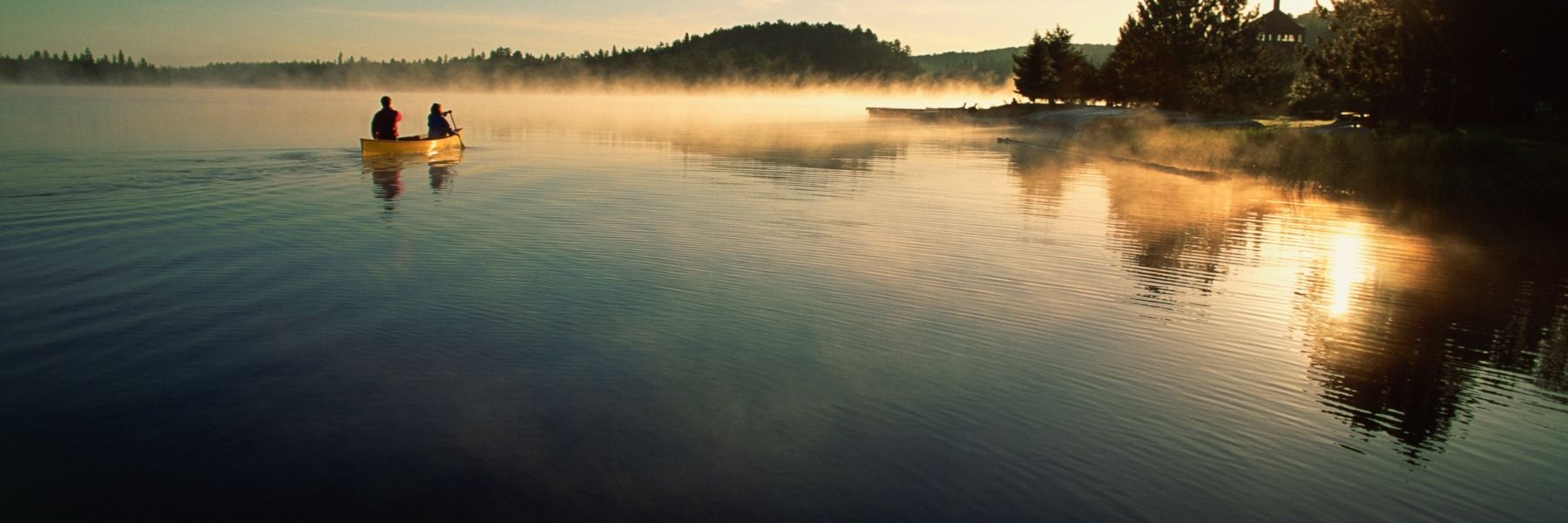 Couple canoeing on lake at sunset.