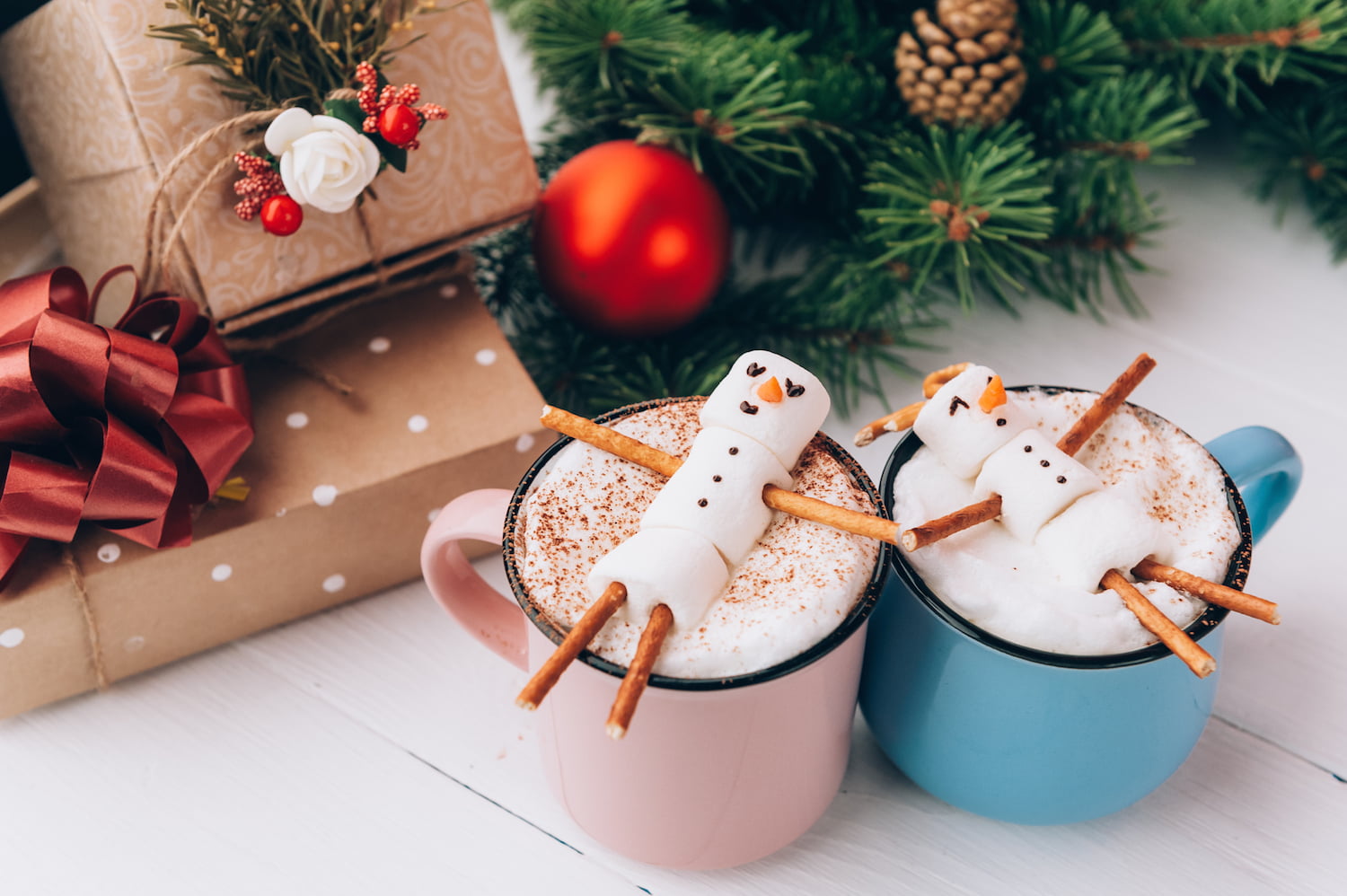 a mug with hot chocolate on a wooden table with a marshmallow man who is resting in a mug